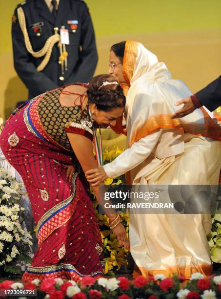 Prime Minister of Trinidad and Tobago Kamla Persad-Bissessar touches the feet of Indian President Pratibha Devisingh Patil after being awarded with...