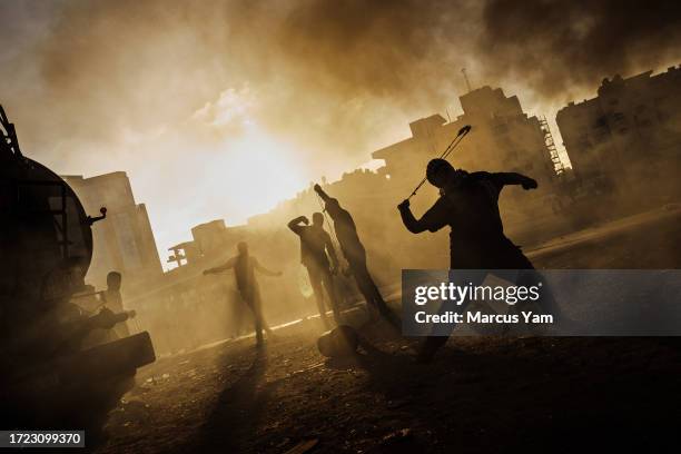 Palestinian boy slings a rock at Israeli forces as local Palestinians protest Israeli occupation in the West Bank, and are met with tear gas,...