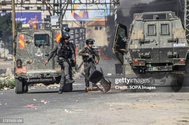 Israeli soldiers kick rubble off the ground placed by Palestinian demonstrators, during a demonstration in support of Gaza, which has been under...