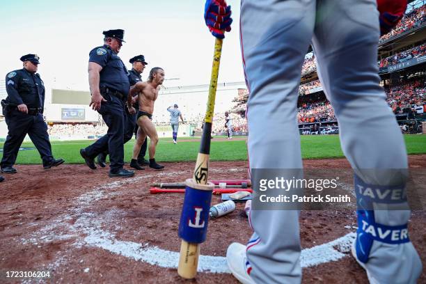 Leody Taveras of the Texas Rangers waits in the on-deck circle as a field invader is apprehended by police during the eighth inning of Game One of...