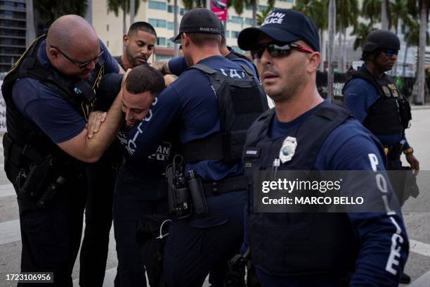 Miami police officers detain a demonstrator as people attend a rally in support of Palestinians in the Gaza Strip at Bayfront Park in Miami, Florida,...