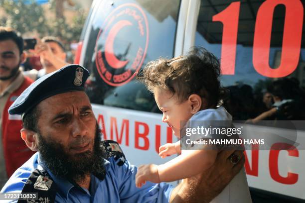 Graphic content / TOPSHOT - A Palestinian police officer holds a baby brought to a hospital following an Israeli strike, in Khan Yunis in the...