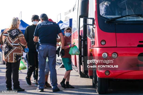 Police officers check immigrants as they board a coach after disembarking from the Medecins Sans Frontieres NGO's ship Geo Barents, docked with 258...