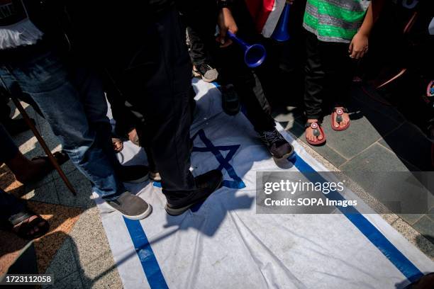 Protesters are seen stepping on the Israeli flag during the protest. Protesters in Kuala Lumpur marched to the US Embassy to support Palestine in the...