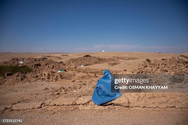 Herat, Afghanistan. An Afghan woman sits and watches the ruined village near Herat after the earthquake.