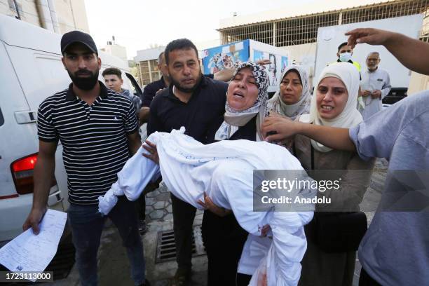 Woman carries a dead body of a child to the morgue of the Suheda al-Aqsa Hospital as Israel's attacks on the Gaza Strip continue on its 8th day in...