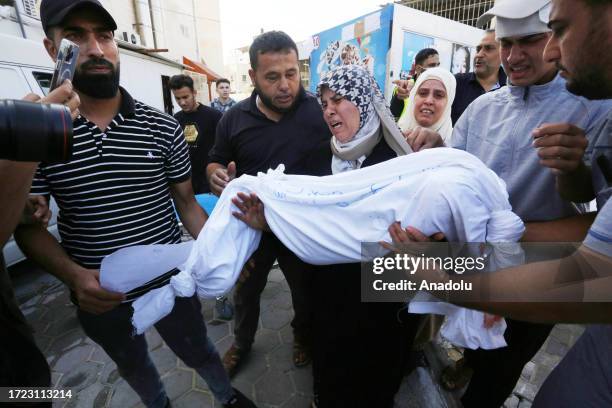 Woman carries a dead body of a child to the morgue of the Suheda al-Aqsa Hospital as Israel's attacks on the Gaza Strip continue on its 8th day in...