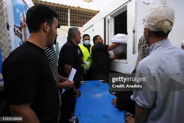 Man carries a dead body to an ice cream refrigerators due to the insufficiency of the hospital morgues at the Suheda al-Aqsa Hospital as Israel's...