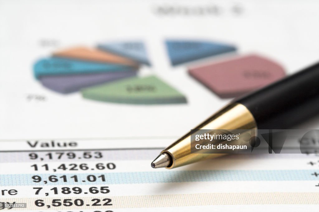 Ballpoint pen on top of numbers and a pie chart