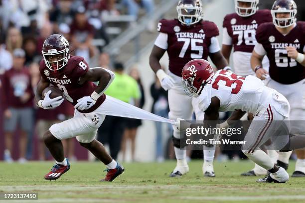 Le'Veon Moss of the Texas A&M Aggies is tackled by Deontae Lawson of the Alabama Crimson Tide in the second half at Kyle Field on October 07, 2023 in...