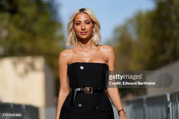 Model Roz wears an off-shoulder on-knee black dress, a leather belt, a mauve leather bag, outside Stella McCartney, during the Womenswear...