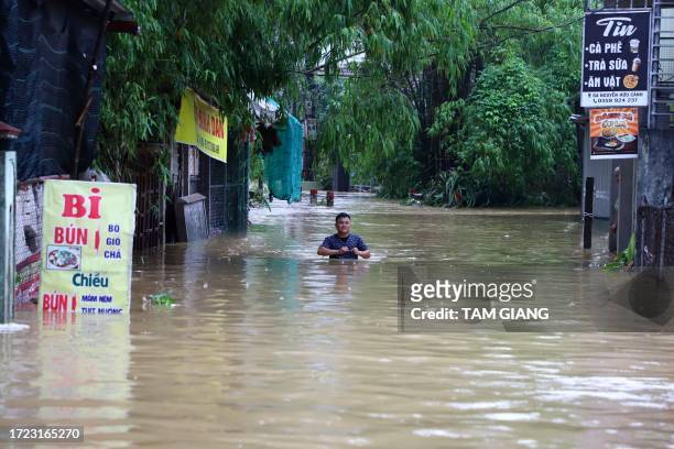 This photo taken on October 13, 2023 shows a man walking through a flooded area of Hue city in central Vietnam. Two people died after being swept...