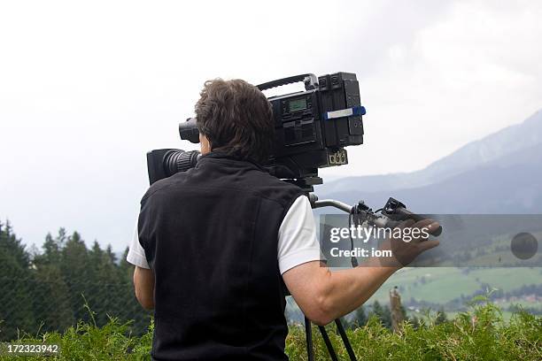 man operating video camera in mountains - film crew studio stock pictures, royalty-free photos & images