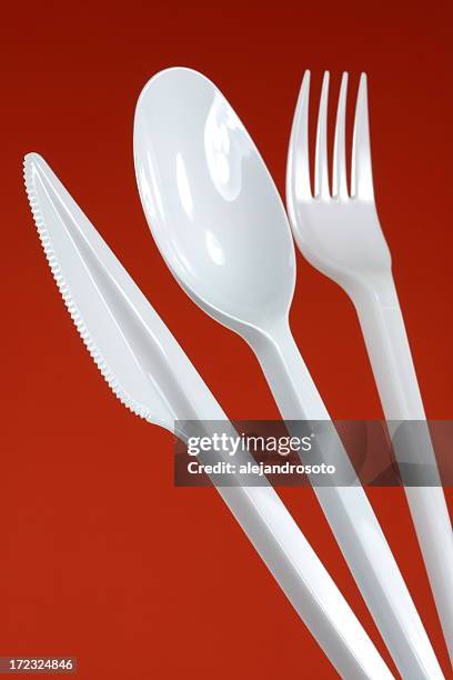 white plastic cutlery on a red background - plastic cutlery stock pictures, royalty-free photos & images