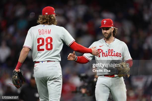 Alec Bohm and Bryce Harper of the Philadelphia Phillies react after defeating the Atlanta Braves during Game One of the Division Series at Truist...