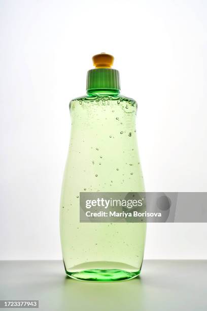 green transparent bottle of dishwashing detergent with bubbles. - soap dispenser stock pictures, royalty-free photos & images
