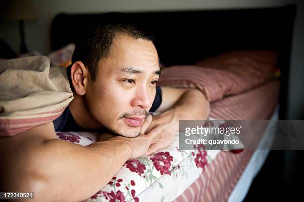 asiatische erwachsener mann ein deprimierter im bett zu hause, textfreiraum - vietnamesischer abstammung stock-fotos und bilder