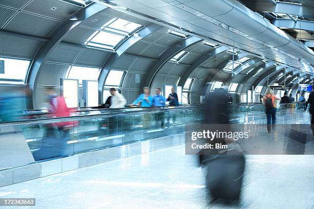 people walking in airport tunnel, pulling luggage, blurred motion - moving walkway airport stock pictures, royalty-free photos & images