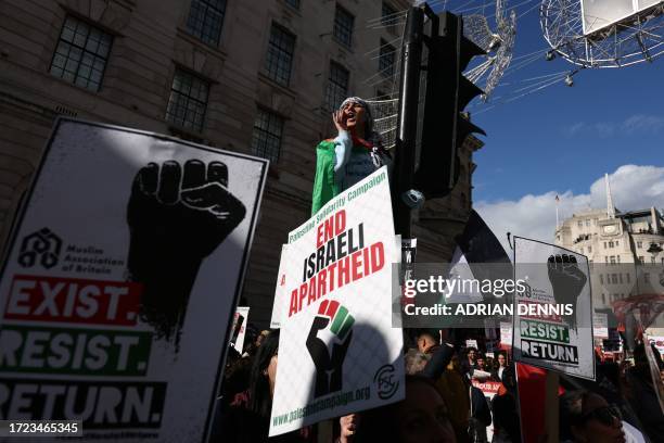 Protester climbs a set of traffic lights as people gather with placards to take part in a 'March For Palestine', part of a pro-Palestinian national...