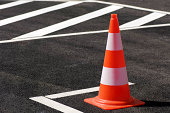 Orange traffic cone sitting on the black top pavement
