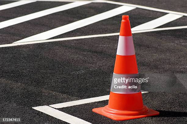 orange traffic cone sitting on the black top pavement - cone shape stock pictures, royalty-free photos & images