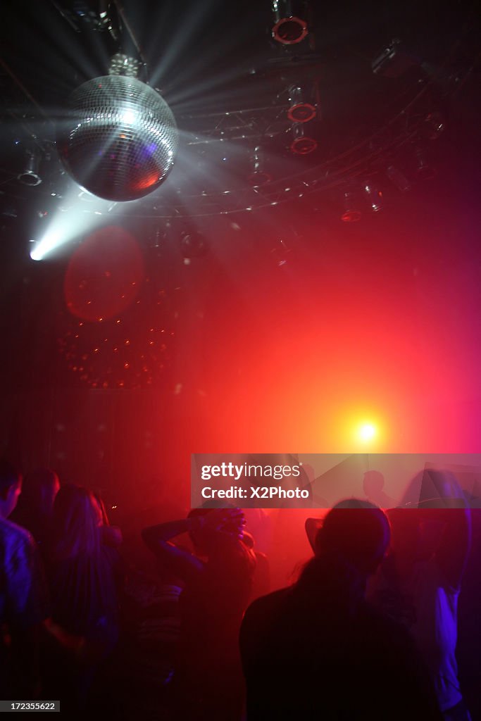 People dancing under a disco ball at a nightclub