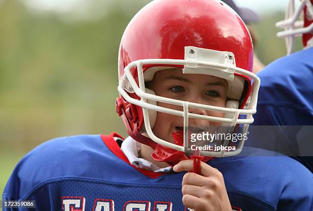 a young boy with an american football uniform - football player face stock pictures, royalty-free photos & images