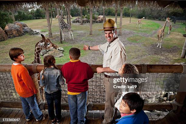 children with zookeeper at giraffe exhibit - zoologists stock pictures, royalty-free photos & images