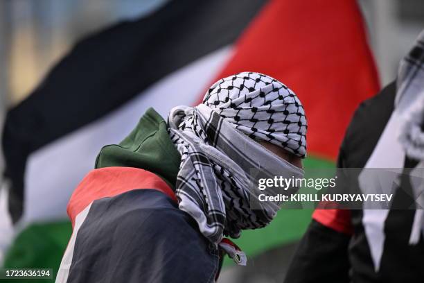 Demonstrator covers his face with a Palestinian scarf during a pro-Palestinian rally in Frankfurt on October 14 after the October 7 Hamas attacks in...