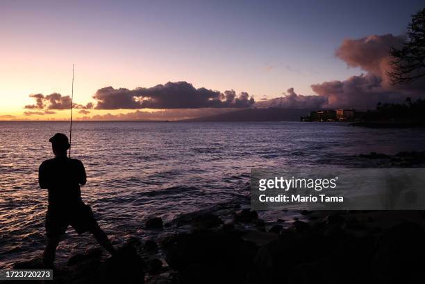 Resident fishes with resort properties in the distance nearly two months after a devastating wildfire on October 07, 2023 in Lahaina, Hawaii. The...