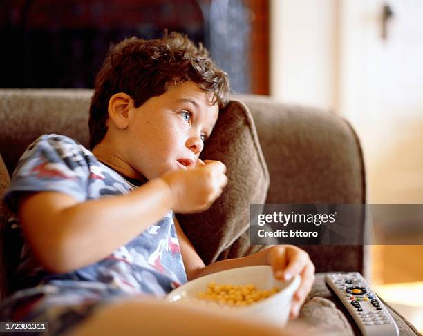 boy eating cereal on couch - boy eating cereal stock pictures, royalty-free photos & images