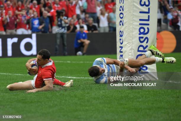 Wales' scrum-half Tomos Williams scores a try ahead of Argentina's full-back Juan Cruz Mallia during the France 2023 Rugby World Cup quarter-final...