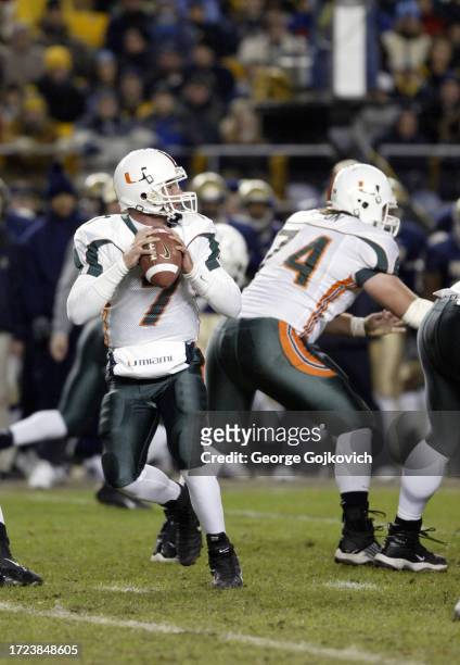 Quarterback Brock Berlin of the University of Miami Hurricanes looks to pass as offensive lineman Eric Barton blocks during a Big East college...