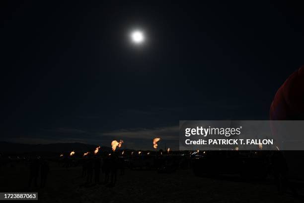 Hot air balloon operators create a "ring of fire" with their gondola burners during the annular solar eclipse at the 51st Albuquerque International...