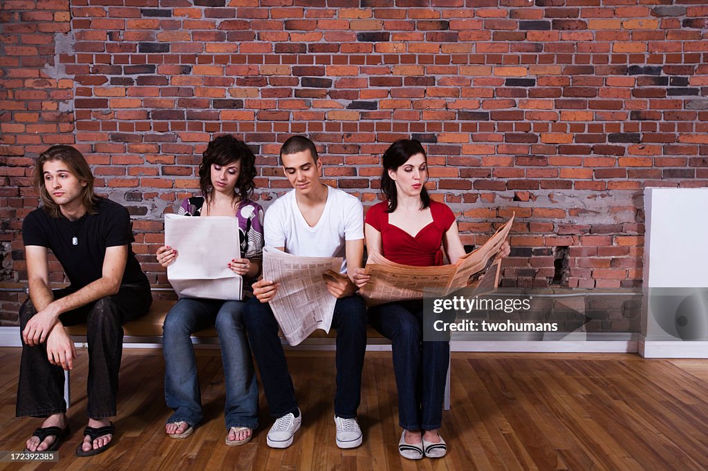 Friends sitting on a bench with three reading a newspaper