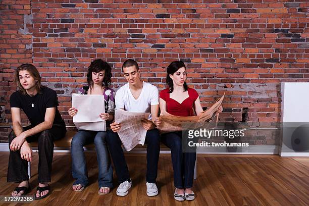 friends sitting on a bench with three reading a newspaper - twohumans stock pictures, royalty-free photos & images