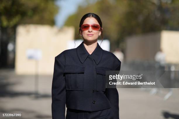 Guest wears red sunglasses, a navy dark blue oversized jacket with pockets and shoulder pads, outside Stella McCartney, during the Womenswear...