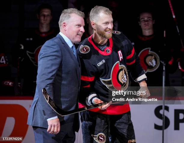 Claude Giroux of the Ottawa Senators is presented a stick by Daniel Alfredsson congratulating him on scoring 1,000 points in his NHL career prior to...