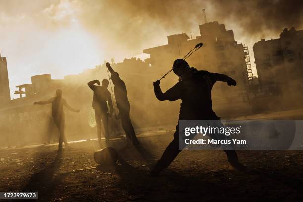 Palestinian boy slings a rock at Israeli forces as local Palestinians protest Israeli occupation in the West Bank, and are met with tear gas,...