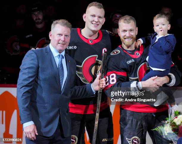 Claude Giroux of the Ottawa Senators pictured holding his son is presented a stick by Daniel Alfredsson and Brady Tkachuk congratulating him on...