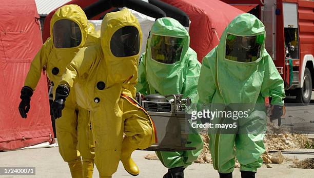 four decontamination operatives at work in green and yellow - biochemical weapon stock pictures, royalty-free photos & images