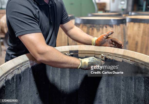 in a sherry cooperage a worker is sealing the inside of a barrel. the photograph is taken from inside the barrel - sherry stock pictures, royalty-free photos & images