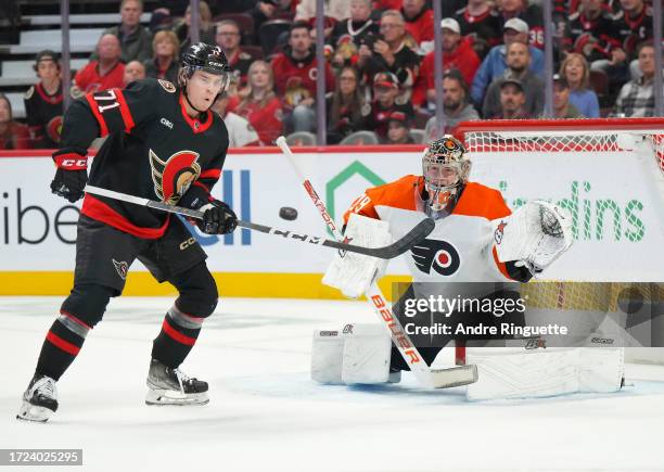 Jakob Chychrun of the Ottawa Senators scores a first period goal against Carter Hart of the Philadelphia Flyers as Ridly Greig looks to deflect the...