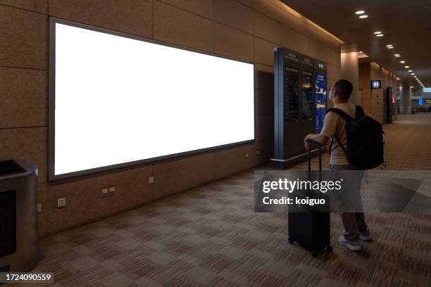 passengers looking at airport billboards - billboard stock pictures, royalty-free photos & images