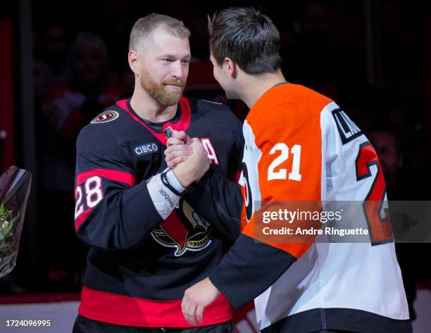 Scott Laughton of the Philadelphia Flyers congratulates Claude Giroux of the Ottawa Senators during a ceremony for his 1,000th point prior to their...