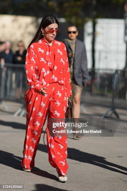 Guest wears red sunglasses, a red shirt with printed white horses, a scarf, flowing pants, outside Stella McCartney, during the Womenswear...