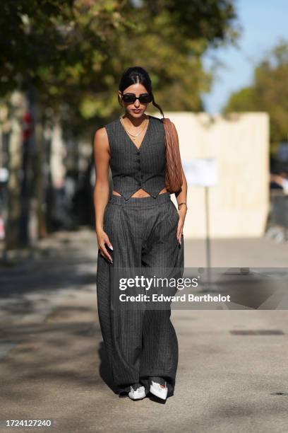 Bettina Looney wears sunglasses, a gray striped waistcoat, a brown leather bag, flared wide leg pants, outside Stella McCartney, during the...