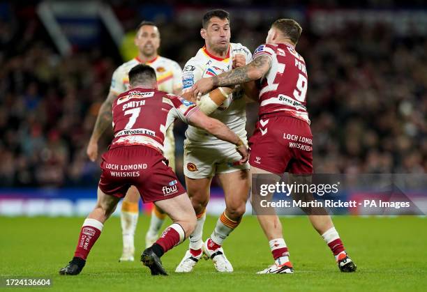 Catalans Dragons' Benjamin Garcia is tackled by Wigan Warriors' Harry Smith and Sam Powell during the Betfred Super League final match at Old...