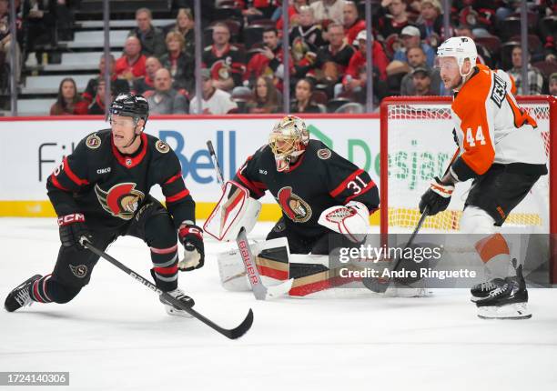 Anton Forsberg of the Ottawa Senators tracks the puck around teammate Jakob Chychrun as Nicolas Deslauriers of the Philadelphia Flyers looks for the...