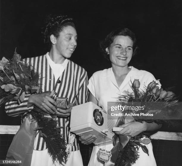 American tennis player Althea Gibson alongside her opponent, American tennis player Nancy Chaffee, both holding timepieces and bouquets following the...